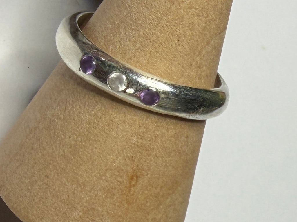 Handmade sterling silver ring with flush set stones. Purple stones and one clear. Size O