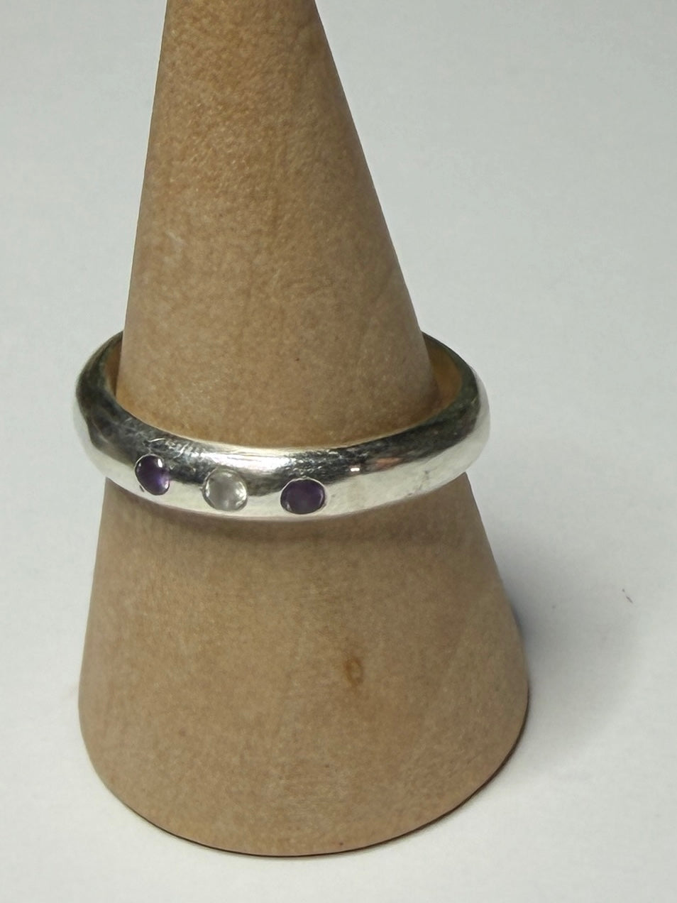 Handmade sterling silver ring with flush set stones. Purple stones and one clear. Size O